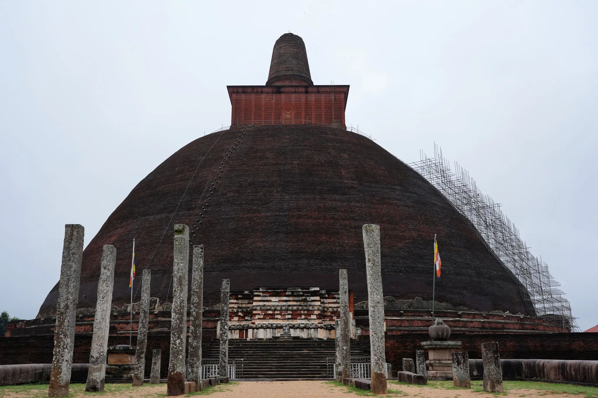 Ancient brick stupa with surrounding pillars.